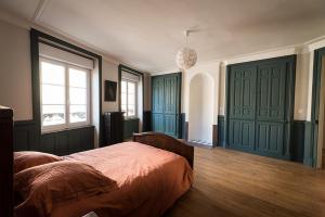 ein Schlafzimmer mit grünen Türen und einem Bett in der Unterkunft Les Gites Historiques in Mirecourt
