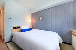 a bedroom with a large white bed with blue pillows at Richmond Hotel Naha Kumoji in Naha