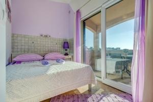 a bedroom with a bed with purple pillows and a balcony at Holiday Home Mirna Vala in Sevid