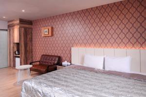 um quarto com uma cama e uma cadeira em Guest Motel- Zhongli Branch em Pingzhen