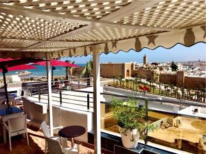 balcón con mesa, sillas y vistas a la ciudad en Hotel des Oudaias, en Rabat