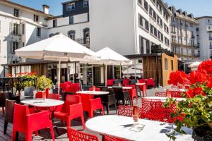 a restaurant with red chairs and tables and umbrellas at H&ocirc;tel Sainte-Rose in Lourdes