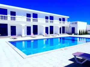 a swimming pool in front of a white building at Del Mare семейный корпус in Kapchagay