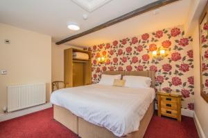 um quarto com uma cama grande com flores na parede em Victoria Inn em Cowbridge