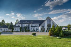 duży biały budynek z czarnym dachem w obiekcie Hotel Junior w Krakowie