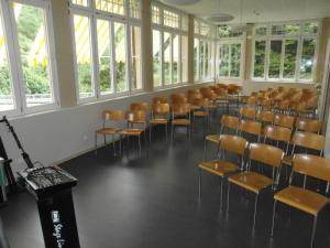 an empty room with chairs and tables and windows at Waldhotel Unspunnen in Interlaken