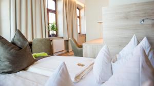 a hotel room with a white bed with pillows at Hotel Angerbräu in Murnau am Staffelsee