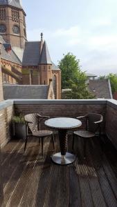 a table and chairs on a balcony with a clock tower at The Bank Hotel in Amsterdam
