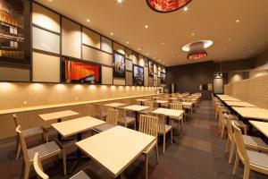 an empty restaurant with wooden tables and chairs at Izumisano Center Hotel Kansai International Airport in Izumi-Sano
