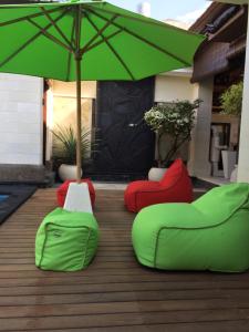 two green chairs and an umbrella on a deck at Villa Nitras in Canggu