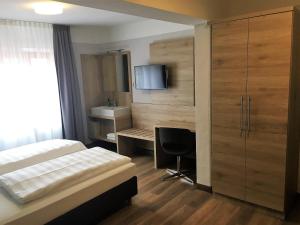 1 dormitorio con 1 cama, escritorio y TV en Eberl Hotel Pension München Feldmoching, en Múnich
