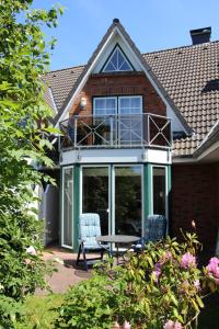 ein Haus mit einer Terrasse mit 2 Stühlen und einem Tisch in der Unterkunft Deichblick in Sankt Peter-Ording