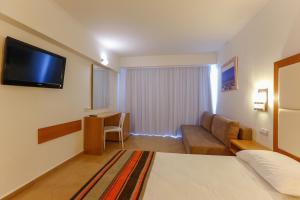 une chambre d'hôtel avec un lit, un canapé et une télévision dans l'établissement Sun Palace Hotel, à Faliraki