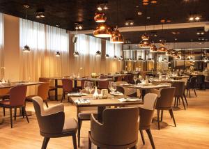 a dining room with tables and chairs and chandeliers at Centennial Nexus Hotel Tallinn in Tallinn
