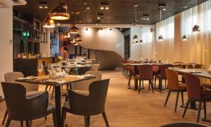 a dining room with tables and chairs and lights at Centennial Nexus Hotel Tallinn in Tallinn