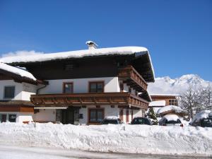 ein schneebedecktes Haus mit davor geparkt in der Unterkunft Gästehaus Sillaber-Gertraud Nuck in Söll