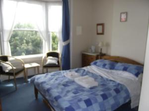 a bedroom with a blue and white bed and a window at beaufort guesthouse in Weymouth