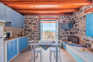 una cocina con armarios azules y una mesa con sillas en Pserimos Villas, en Psérimos