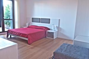 um quarto branco com uma cama com um cobertor vermelho em Four Rooms Guesthouse em Oristano