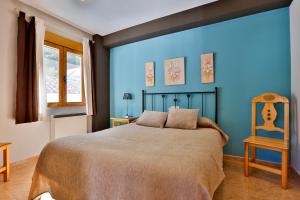 1 dormitorio azul con 1 cama y 1 silla en Apartamentos Castillo Cazorla en Cazorla