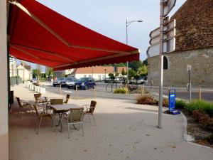Marigny-le-ChâtelにあるLa Renaissanceの通り沿いの赤い傘下のテーブルと椅子
