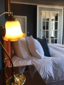 a bed with white pillows and a lamp on a table at Castel De La Terrasse in Étretat