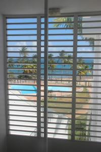een uitzicht op een zwembad door een raam met jaloezieën bij Colibri des îles in Le Gosier
