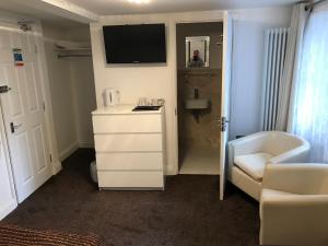 ein kleines Zimmer mit einer weißen Kommode und einem TV in der Unterkunft St George Hotel Great Yarmouth in Great Yarmouth