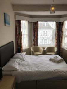 a bedroom with a bed and two chairs and a window at St George Hotel Great Yarmouth in Great Yarmouth