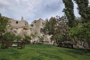 a yard with picnic tables in front of a castle at Dreams Cave Hotel in Ortahisar