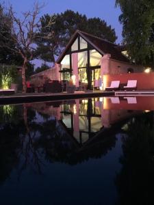 una casa con algunas sillas y un reflejo en el agua en Chambre d’hotes Le Grand Fourneau en Lassay-sur-Croisne