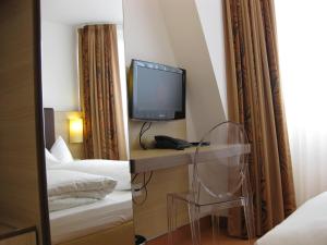 a hotel room with a tv and a mirror at Hotel Flandrischer Hof in Cologne