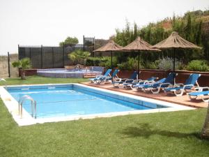 einen Pool mit Stühlen und Sonnenschirmen im Hof in der Unterkunft Hotel Rural Restaurante Los Rosales in Almadén