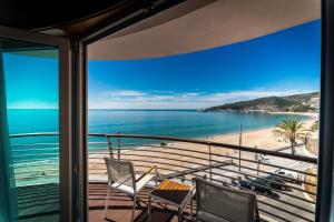 a balcony with chairs and a view of the beach at SANA Sesimbra Hotel in Sesimbra