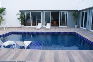 a swimming pool with chairs and a house at Hotel Abba Goiana PE in Goiana