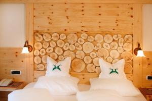 two beds in a room with a wall of logs at Hotel Edda in Selva di Val Gardena