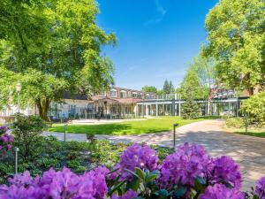 un jardín con flores púrpuras frente a un edificio en Hotel Landhaus Ammann en Hannover