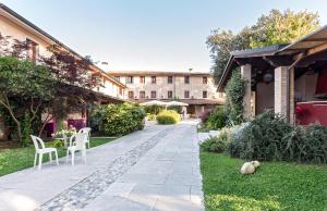 un patio con mesa y sillas y un edificio en Hotel Al Posta, en Casarsa della Delizia