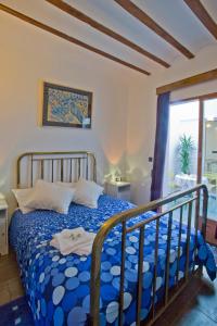 a bedroom with a bed with a blue comforter at La Casa del Balcón in Caravaca de la Cruz