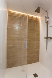 La salle de bains est pourvue d'une douche et d'une porte en bois. dans l'établissement SunShine Puerta de San Francisco, à Cordoue