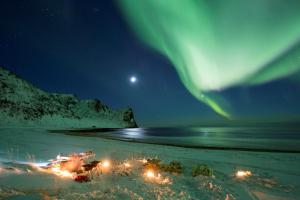 vista para uma praia sob a aurora boreal em Unstad Arctic Resort em Unnstad