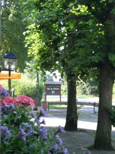 Hotel Up de Birke في Ladbergen: وجود علامة في حديقة بها الزهور والأشجار
