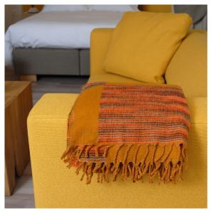a yellow couch with a colorful blanket on it at Les logis de l'horloger in La Chaux-de-Fonds