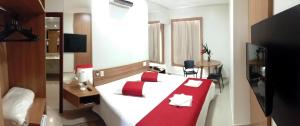 a bedroom with a large white bed with red pillows at Guines Palace Hotel in Patrocínio