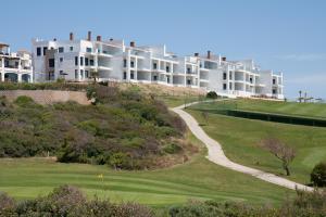 アルカイデサにあるLuxury Apartment Sea, Golf and Gibraltar Viewの緑の庭のある丘の上のアパートメント