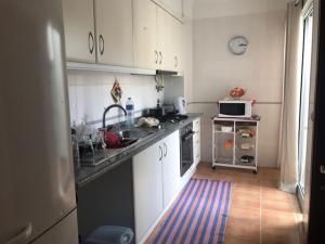 eine Küche mit weißen Schränken und einer Spüle und einer Mikrowelle in der Unterkunft Apartamento Arrifes in Porto Santo