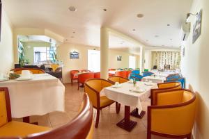 a restaurant with white tables and yellow chairs at Alojamento Bela Vista in Lajes do Pico