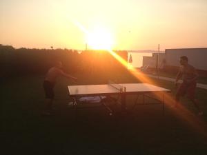 two men playing a game of ping pong at sunset at Sunset Beach Apartmanház in Balatonvilágos