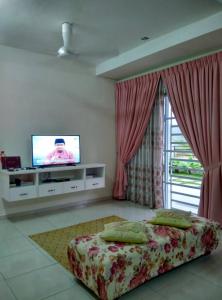 a bedroom with a bed and a flat screen tv at Homestay Mama D'Chandan in Kuala Kangsar
