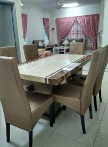 uma mesa de jantar com cadeiras e um sofá em Homestay Mama D'Chandan em Kuala Kangsar